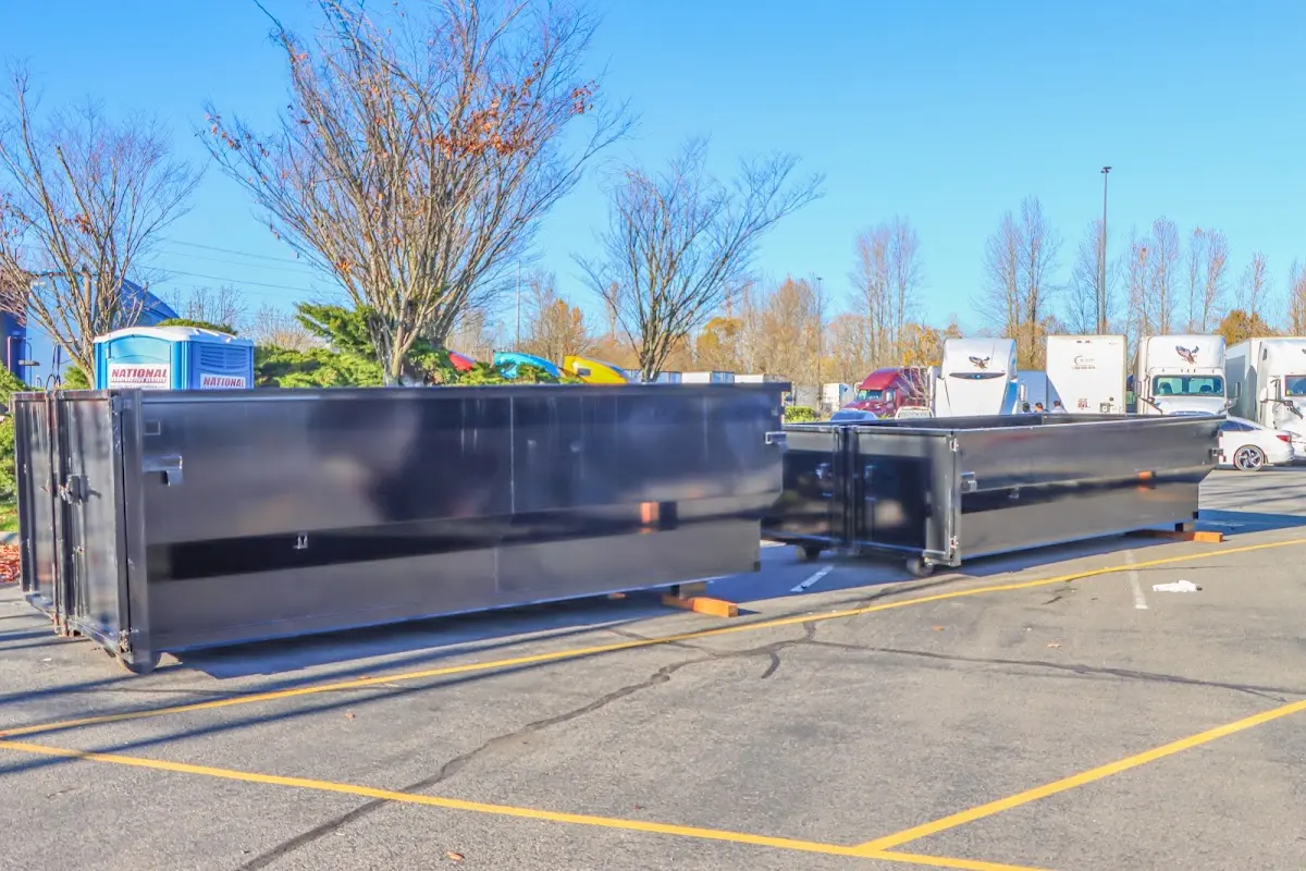 Professional dumpster rental service with roll-off container on residential driveway in Ash